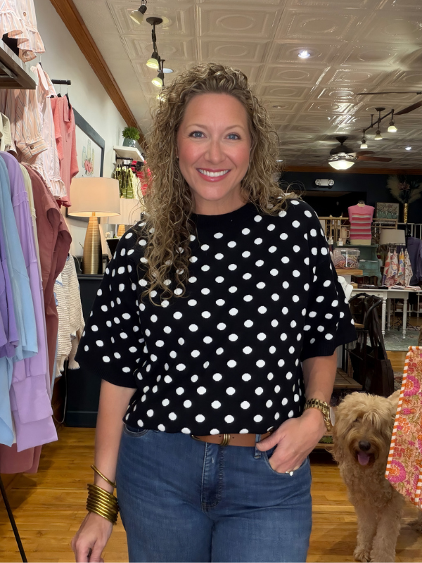 Woman wearing a black polka dot shirt in a store setting with a dog.