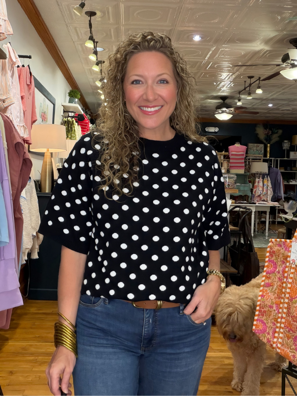 Woman wearing a black polka dot shirt in a store setting with a dog.