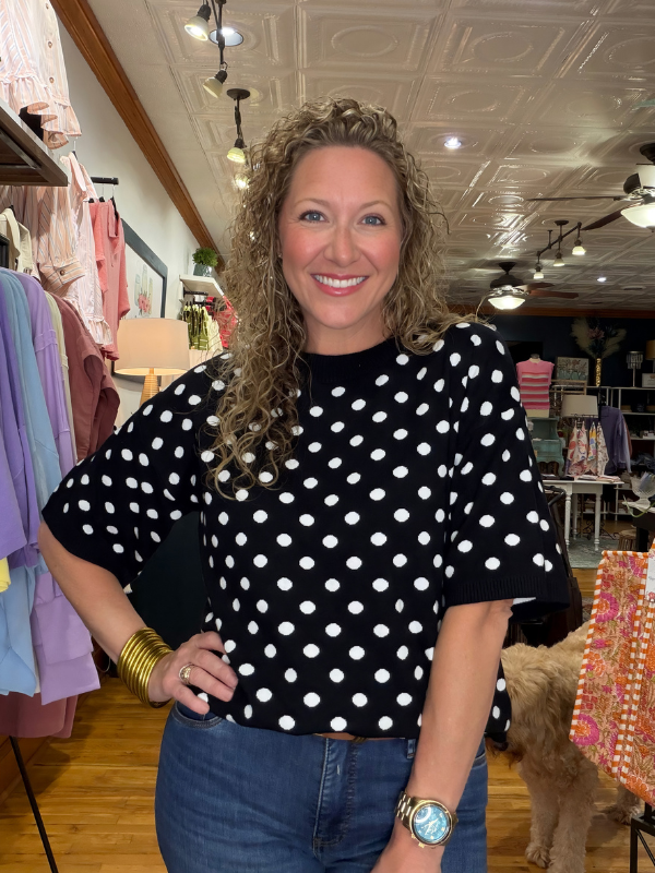 Woman wearing a black polka dot shirt in a store setting