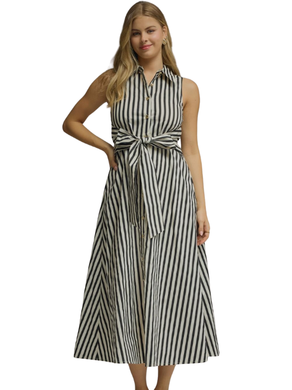 A woman modeling a sleeveless midi dress with vertical black and off-white stripes, featuring a tie waist and button-up collar, set against a plain white background.