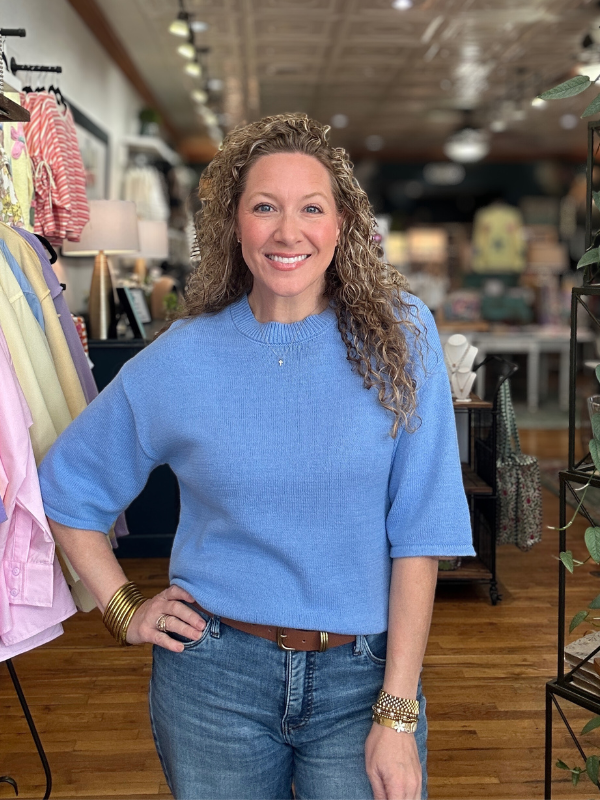 Woman wearing a blue sweater and jeans in a store setting
