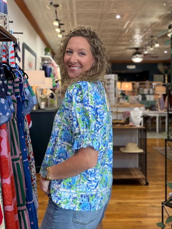 Woman wearing a blue floral shirt in a store setting