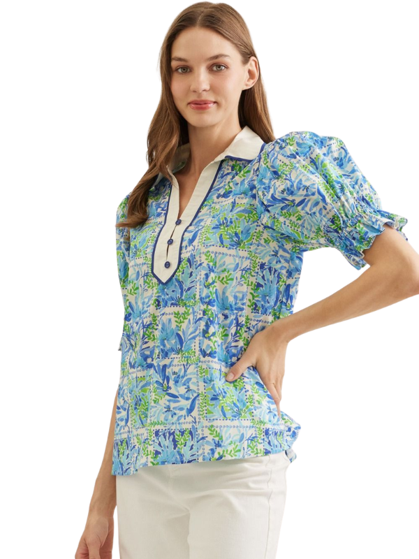 Woman wearing a colorful floral blouse with a white collar on a white background