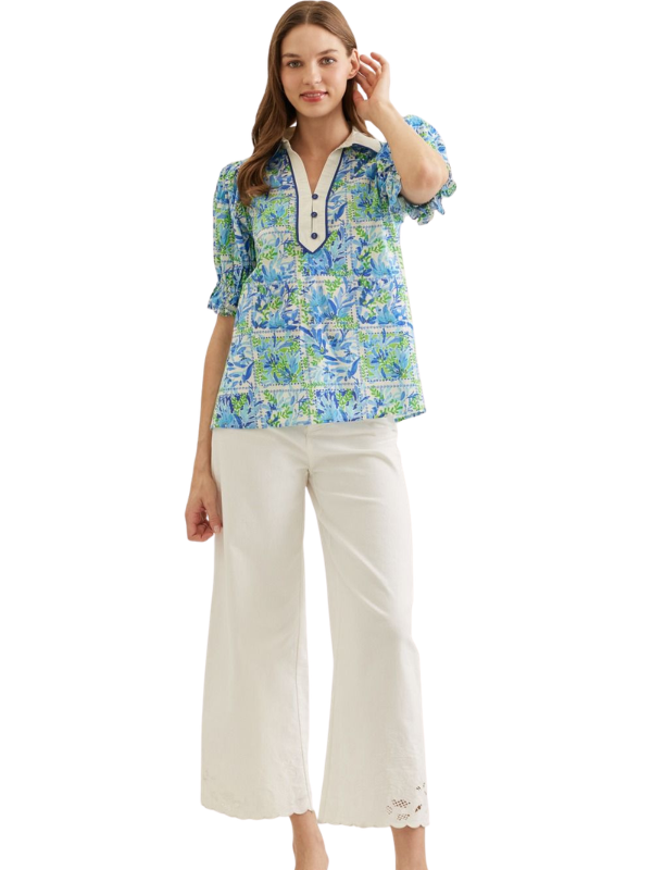 Woman wearing a floral blouse and white pants on a white background
