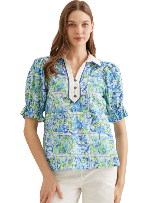 Woman wearing a blue floral blouse with a white collar on a white background