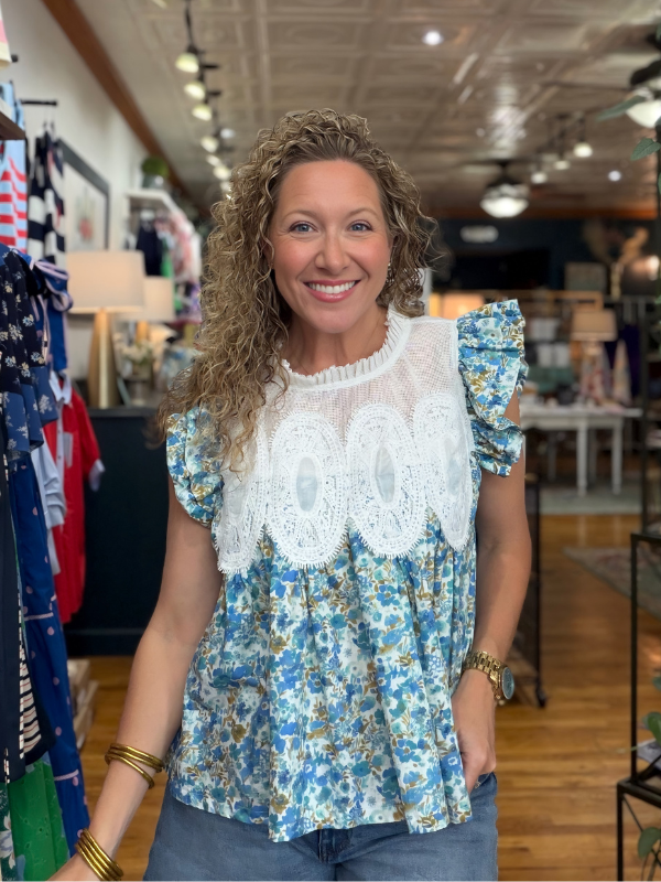 Woman wearing a floral blouse with lace details in a store setting