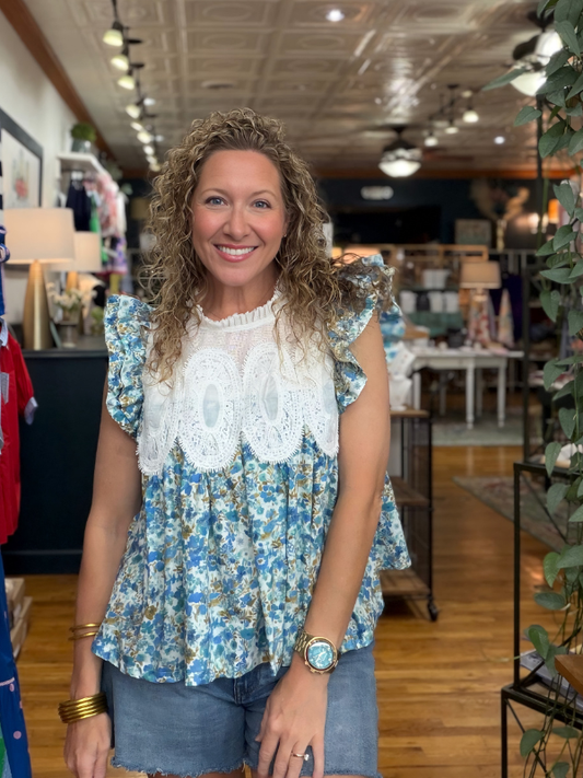 Woman wearing a floral blouse with lace details in a store setting
