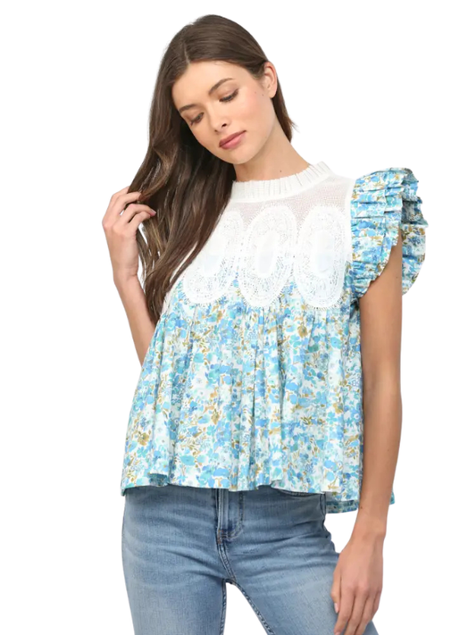 Woman wearing a blue floral top with white lace details on a white background