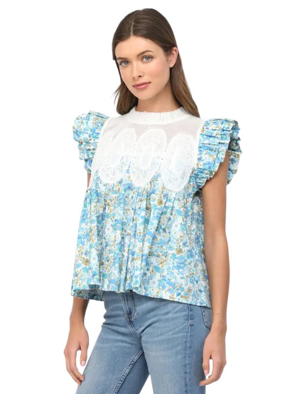 Woman wearing a blue floral blouse with white lace details on a white background