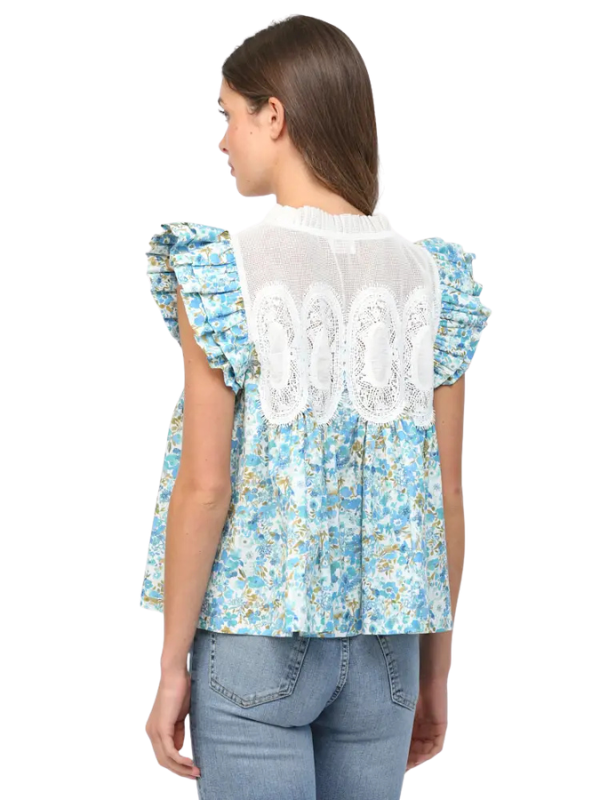 Woman wearing a blue floral blouse with lace details on a white background