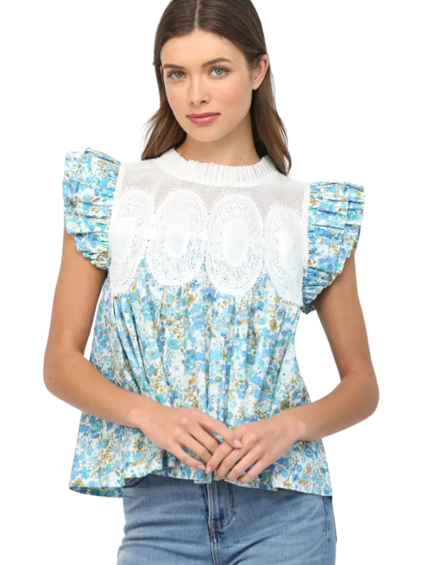 Woman wearing a blue floral top with white ruffled details on a white background