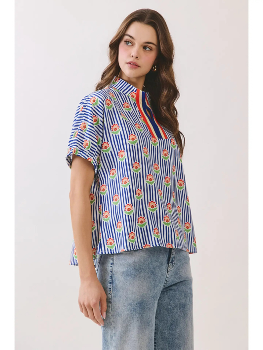 Woman wearing a colorful striped shirt with floral patterns on a plain background