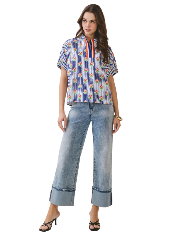 Woman wearing a patterned blouse and blue jeans on a white background