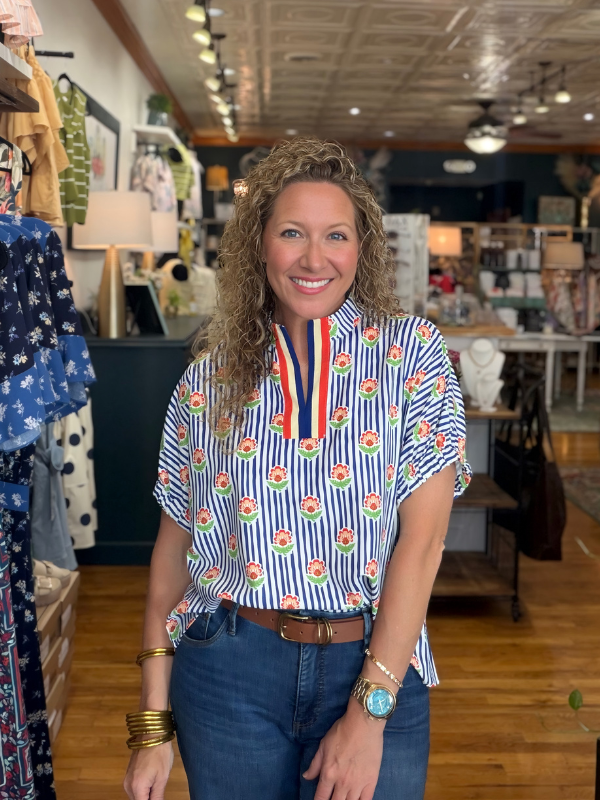 Woman wearing a colorful striped shirt with a patterned collar in a store setting