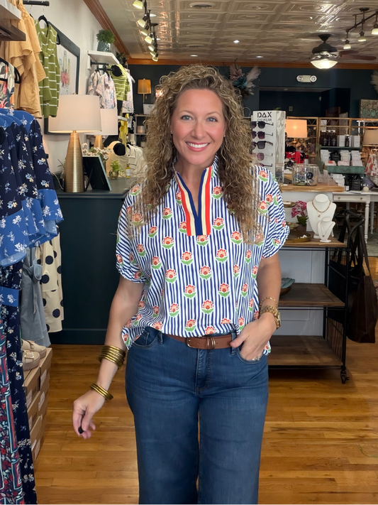 Woman standing in a store wearing a colorful shirt and blue jeans