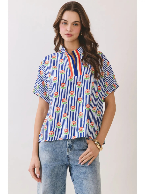 Woman wearing a blue and white patterned shirt with short sleeves against a plain background