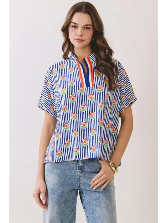 Woman wearing a blue and white patterned shirt with short sleeves against a plain background