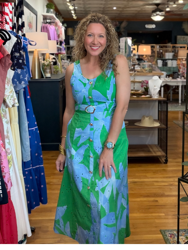 Woman in a green and blue dress standing in a clothing store.