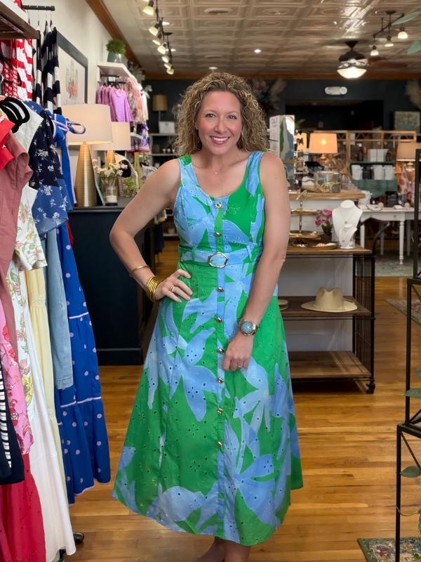 Woman in a green and blue dress standing in a clothing store.