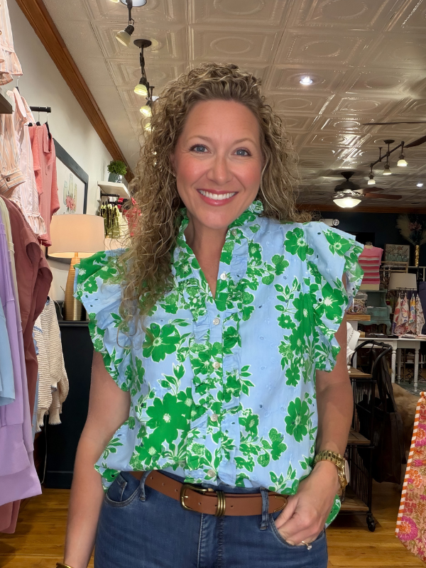 Woman wearing a green floral blouse in a store setting