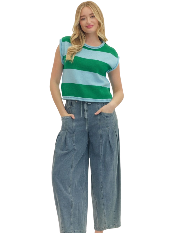 Woman wearing a green and blue striped top with wide-leg jeans on a white background