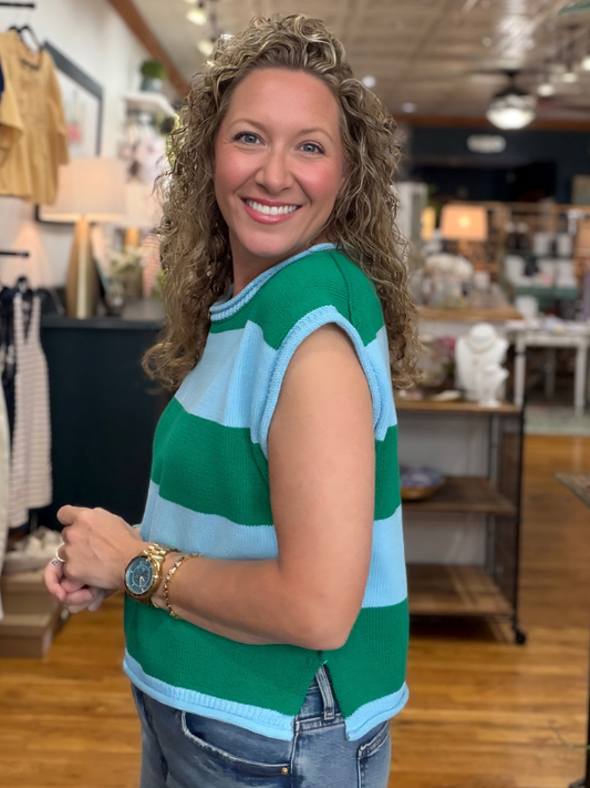 Woman wearing a green and blue striped sleeveless top in a store setting