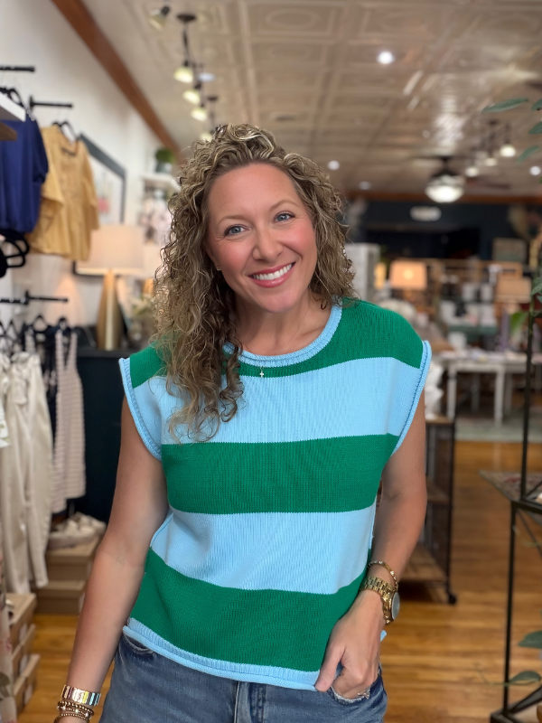 Woman wearing a green and blue striped sleeveless sweater in a store setting