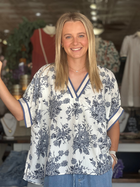 Woman wearing a blue floral blouse in a clothing store setting