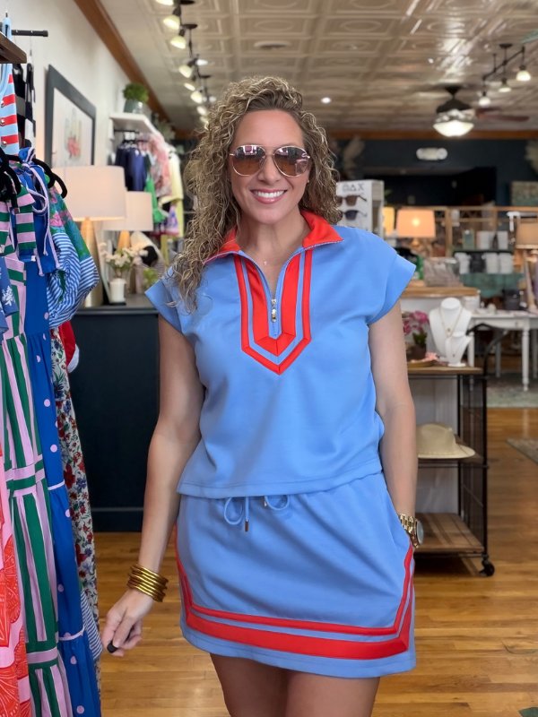 Woman wearing a blue dress with red accents in a store setting
