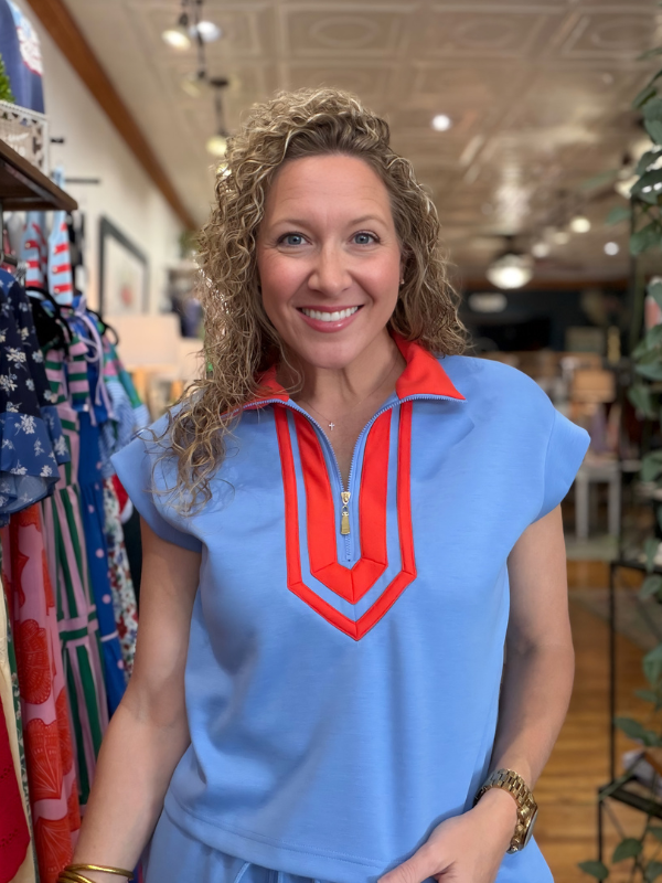 Woman wearing a blue top with red accents in a store setting