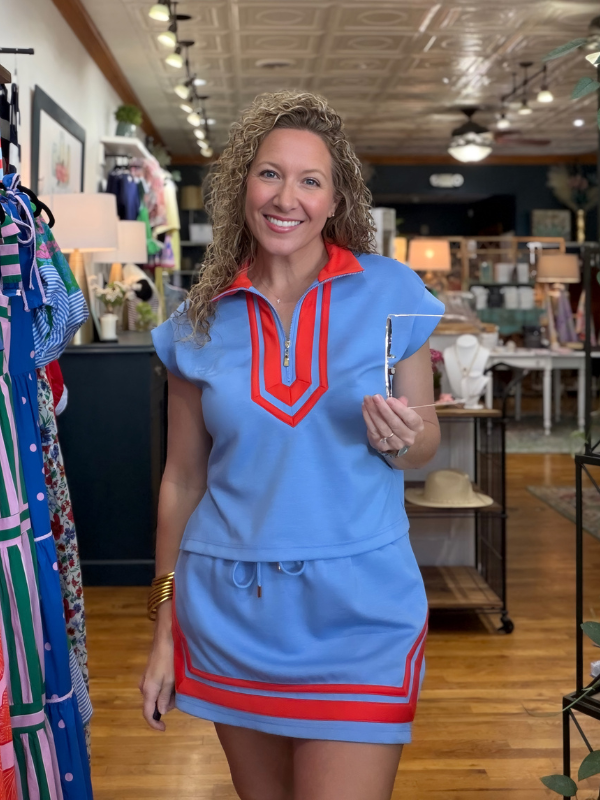 Woman wearing a blue dress with red accents in a store setting