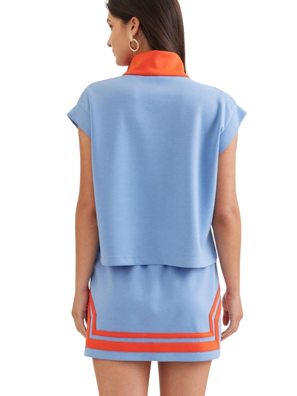 Woman wearing a light blue outfit with orange accents on a white background