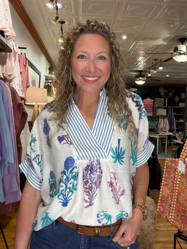 Woman wearing a colorful blouse with feather patterns in a store setting