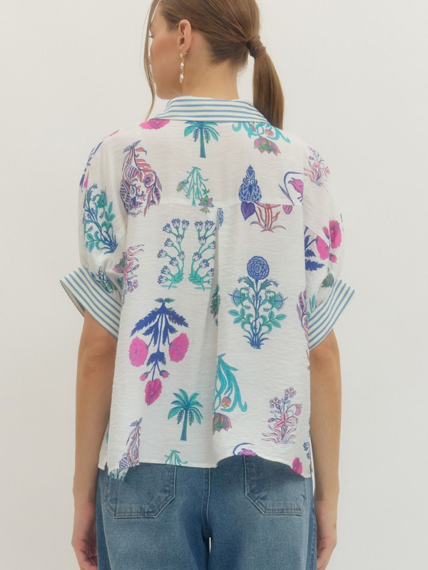 Person wearing a colorful floral patterned shirt with blue jeans on a white background