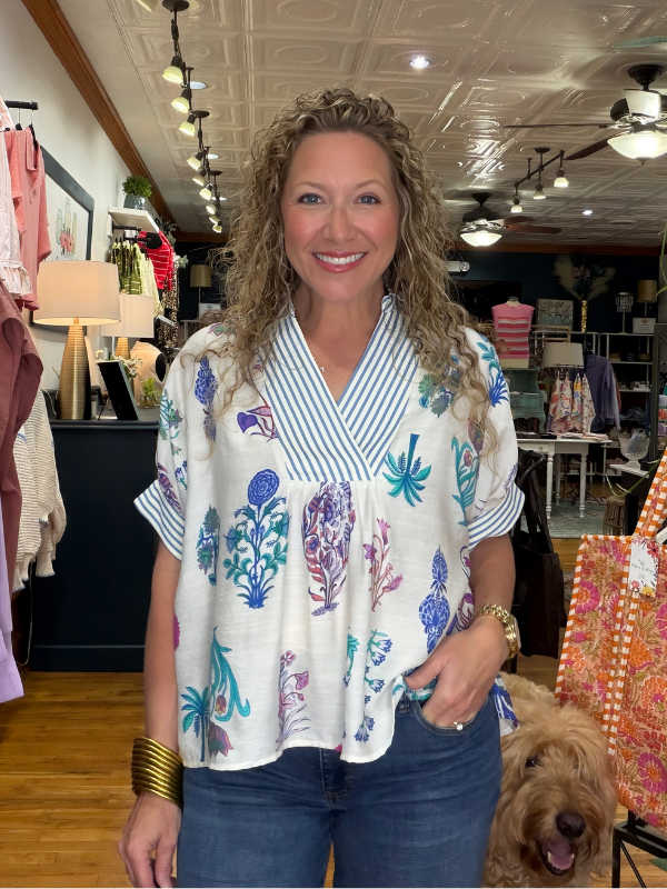 Woman wearing a floral blouse in a store setting with a dog nearby