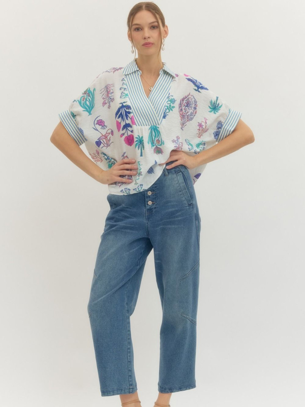 Woman wearing a colorful patterned blouse and blue jeans on a white background
