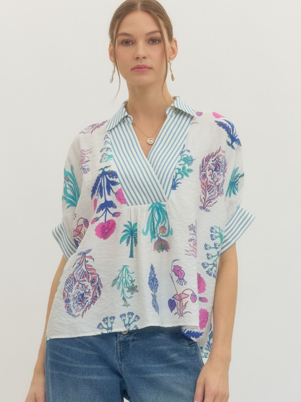 Woman wearing a colorful patterned blouse with a plain background