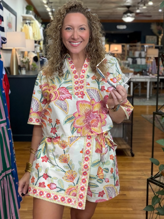 Woman wearing a floral dress holding a phone in a store setting