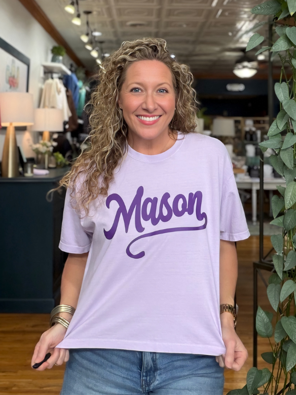 woman wearing a light purple boxy tee that says Mason in dark purple ink 