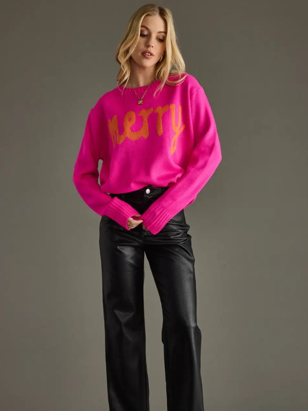 Woman wearing a bright pink sweater with yellow text against a gray background