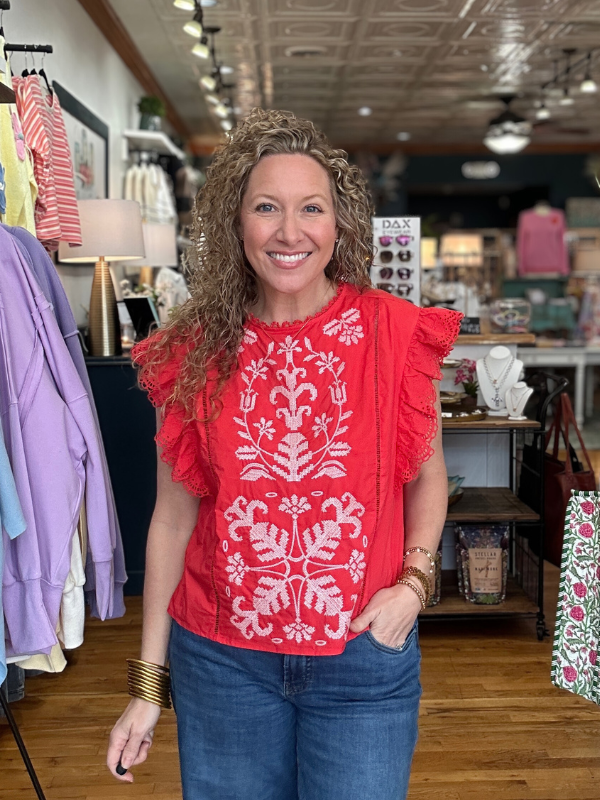 Woman wearing a red blouse with white patterns in a store setting