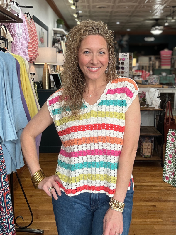 Woman wearing a colorful striped sleeveless top in a store setting