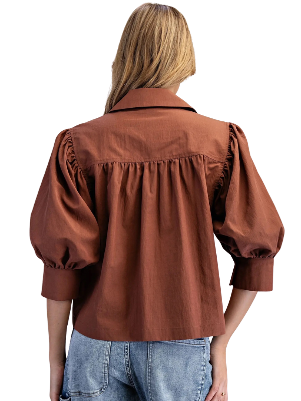 woman wearing bronze puff sleeve top with jeans