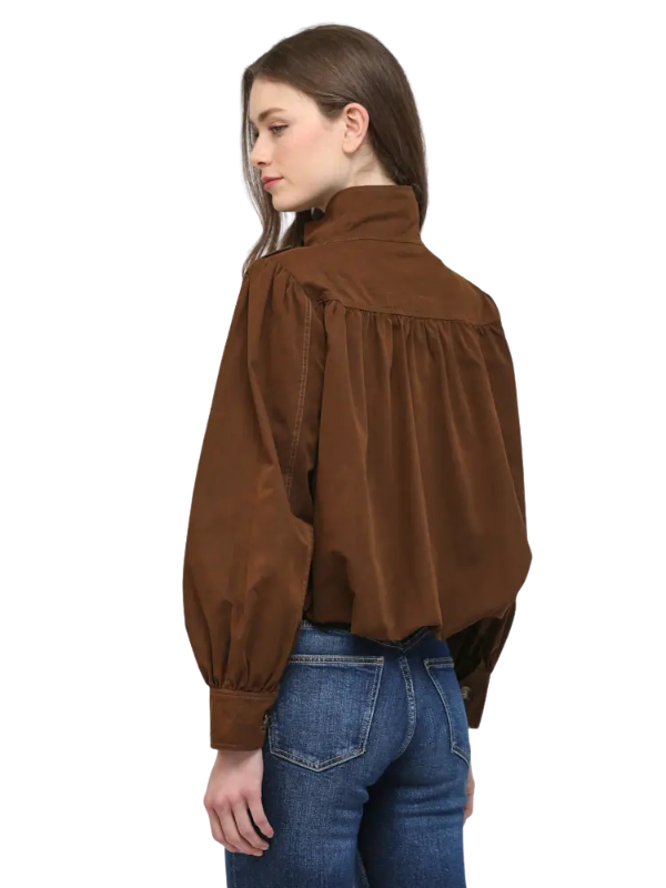 A woman shown from the back wearing a brown long-sleeve blouse with a high gathered collar and voluminous sleeves, paired with blue jeans, against a plain white background.