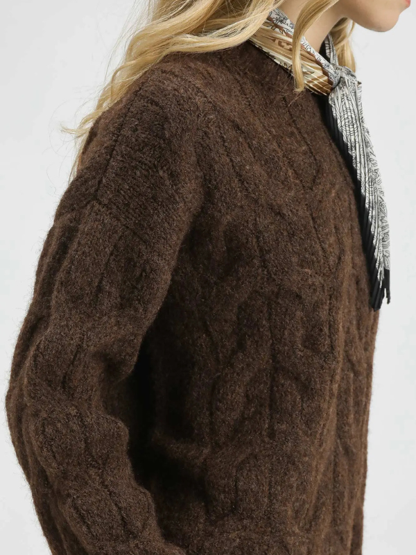 Brown cable knit sweater worn by a person on a white background