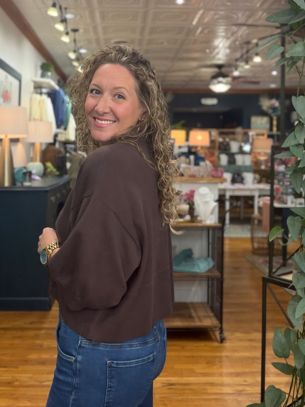 A woman wearing a dark brown knit polo sweater with jeans
