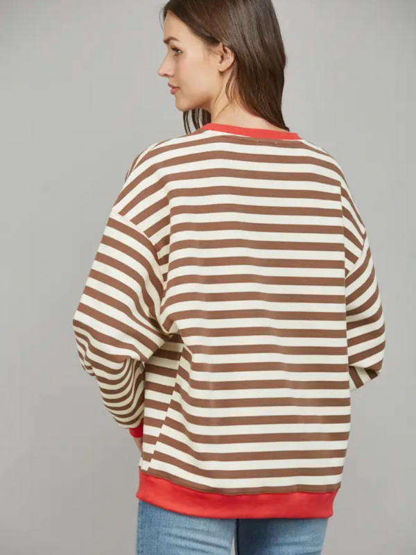 Woman wearing a brown and beige striped sweater with red trim on a gray background