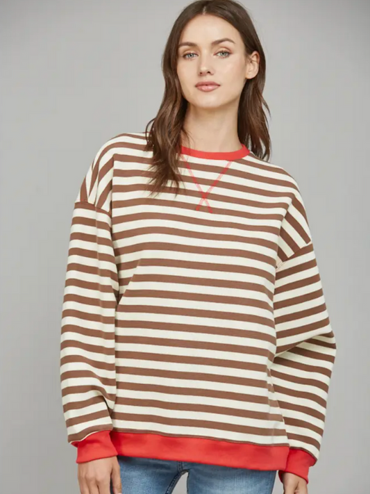 Woman wearing a brown and beige striped sweater with red trim on a gray background