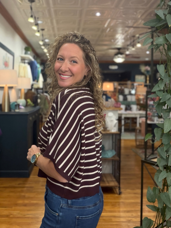 woman wearing a brown and cream dolman sleeve top and jeans