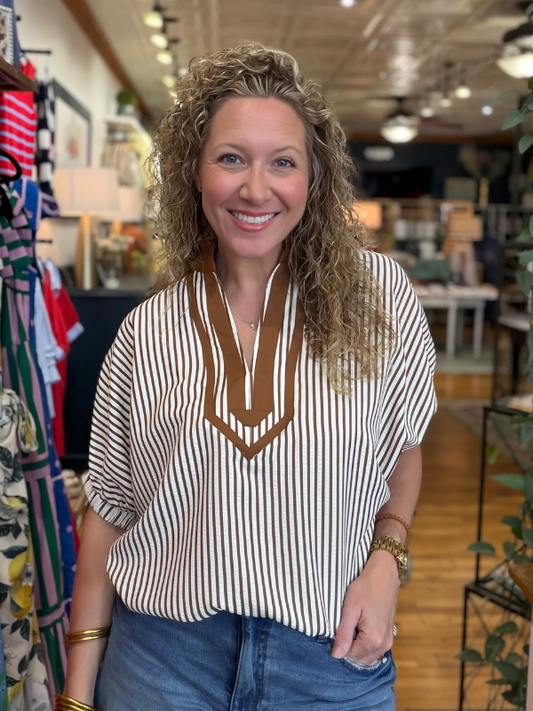Woman wearing a striped shirt with a V-neck design in a store setting